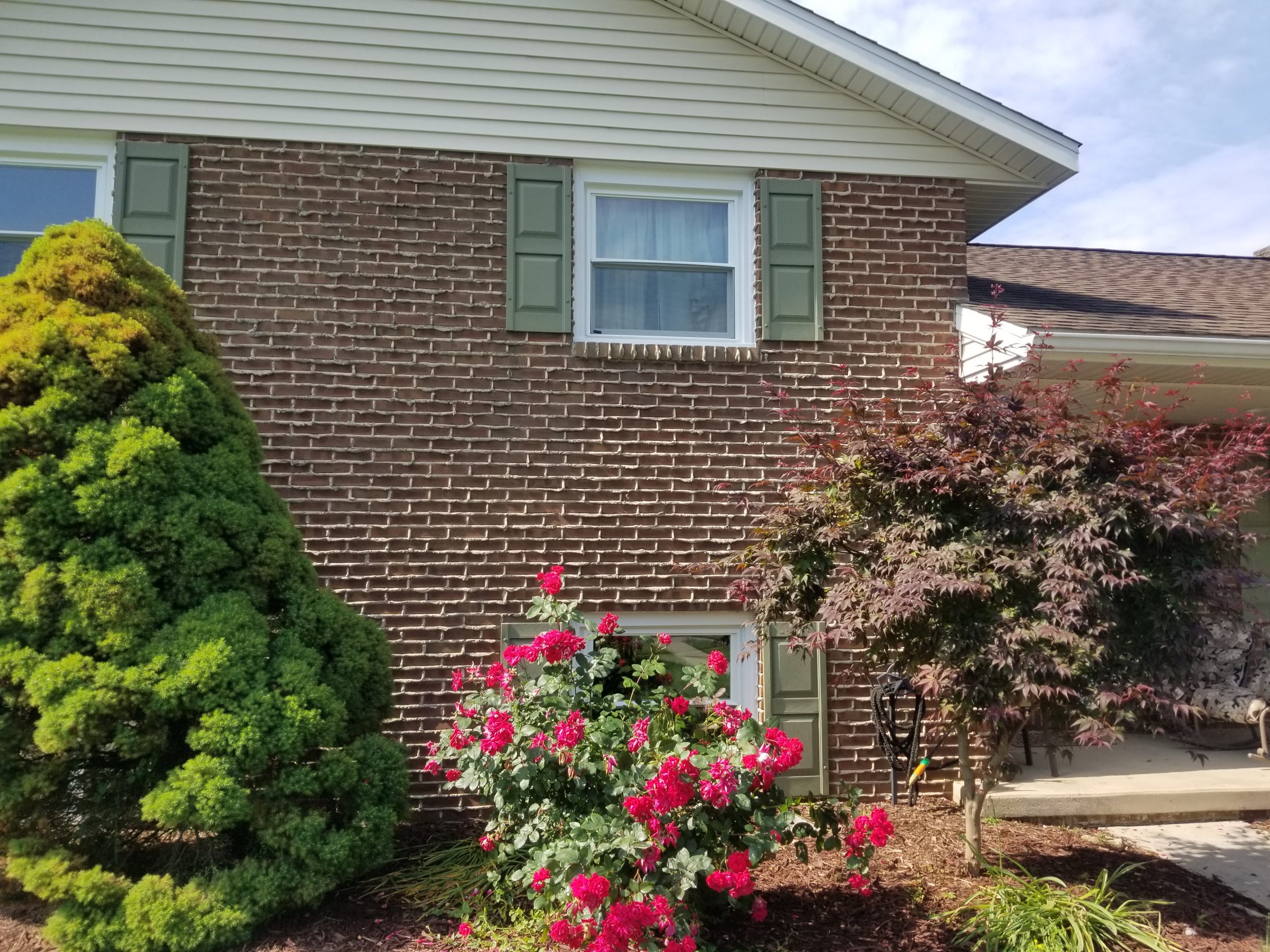 new windows installed with green shutters on a brick wall